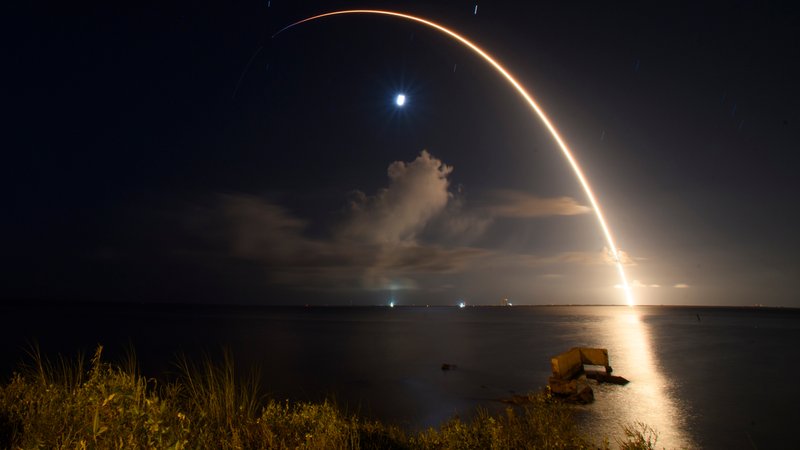 Start einer Falcon-9-Rakete von SpaceX über dem Meer, als heller Lichtbogen zu sehen. | Bild: picture alliance / ZUMAPRESS.com | Jennifer Briggs Start einer Falcon-9-Rakete von SpaceX über dem Meer, als heller Lichtbogen zu sehen.