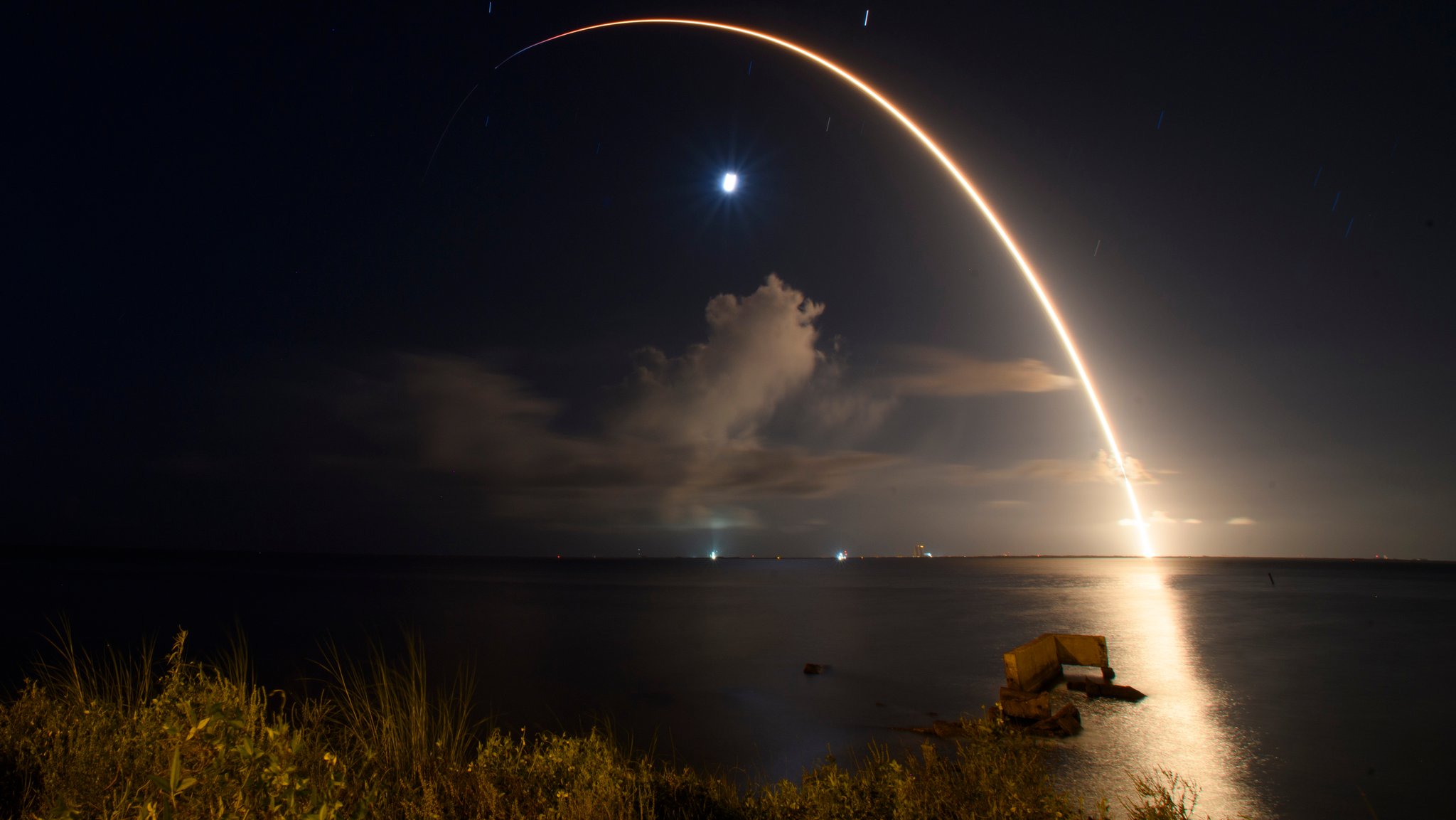 Start einer Falcon-9-Rakete von SpaceX über dem Meer, als heller Lichtbogen zu sehen.