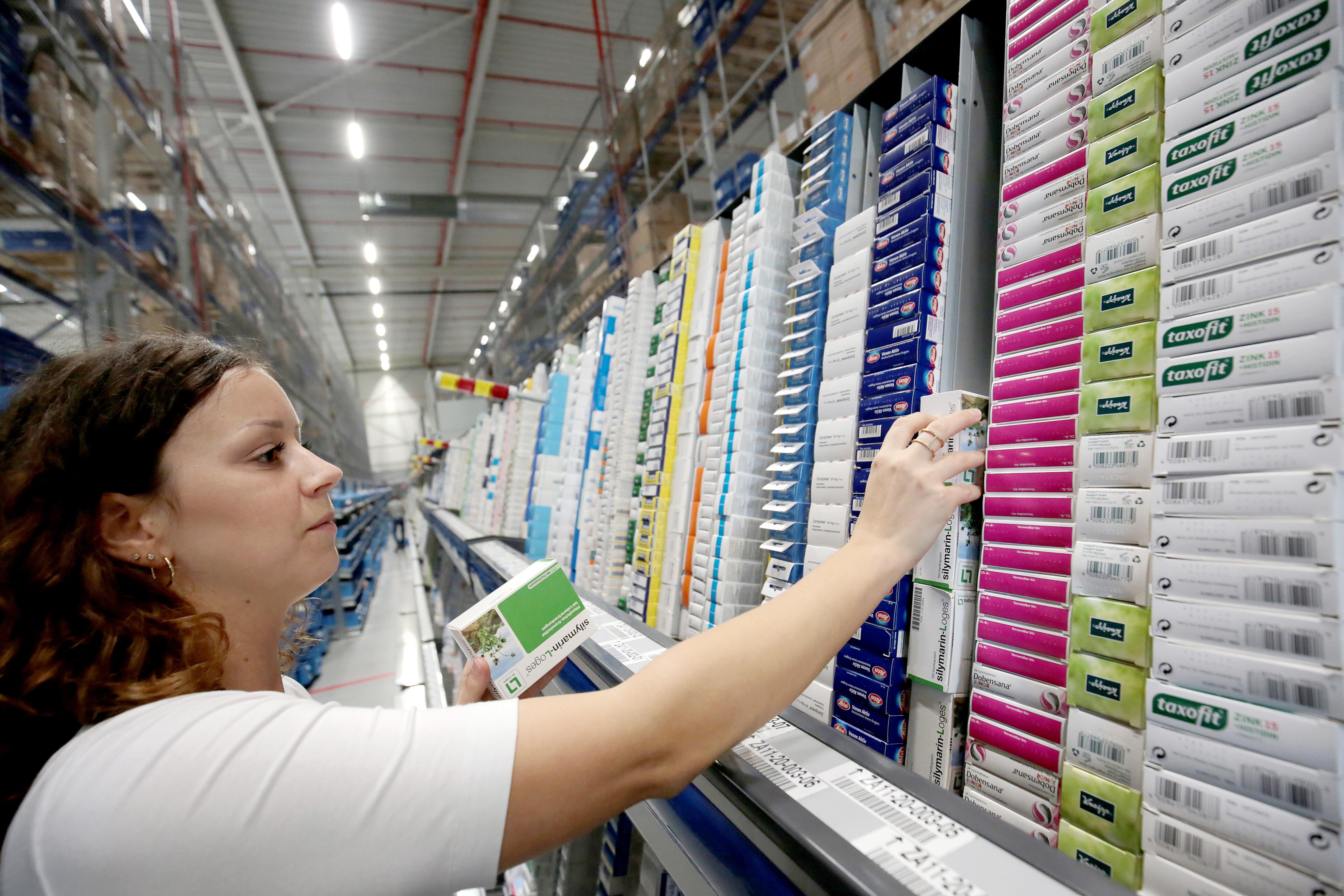 Eine Frau sortiert im Logistik Zentrum der Versandapotheke DocMorris Medikamente.