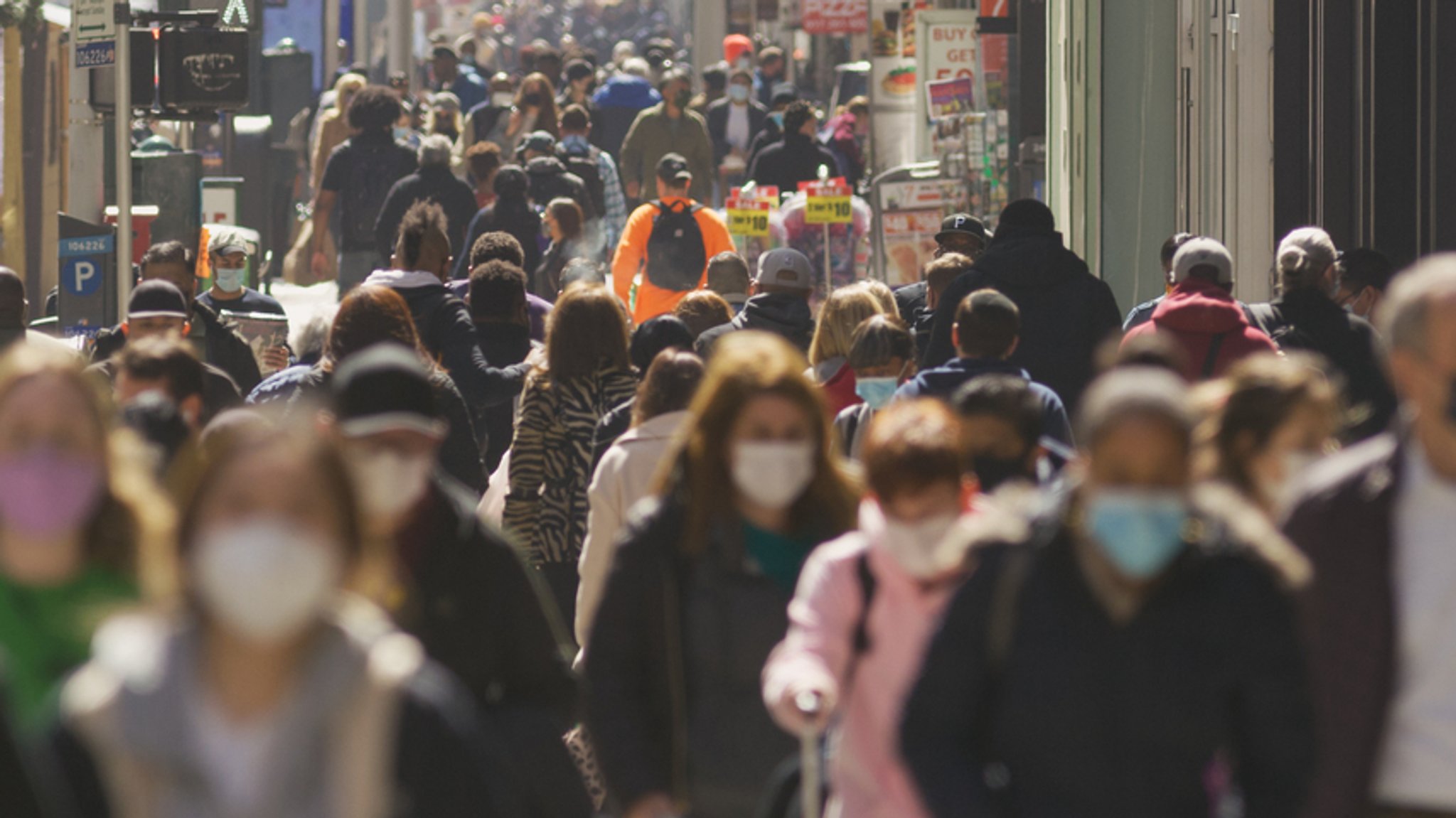 Menschen mit einer Mund-Nasen-Maske gehen auf einer Straße