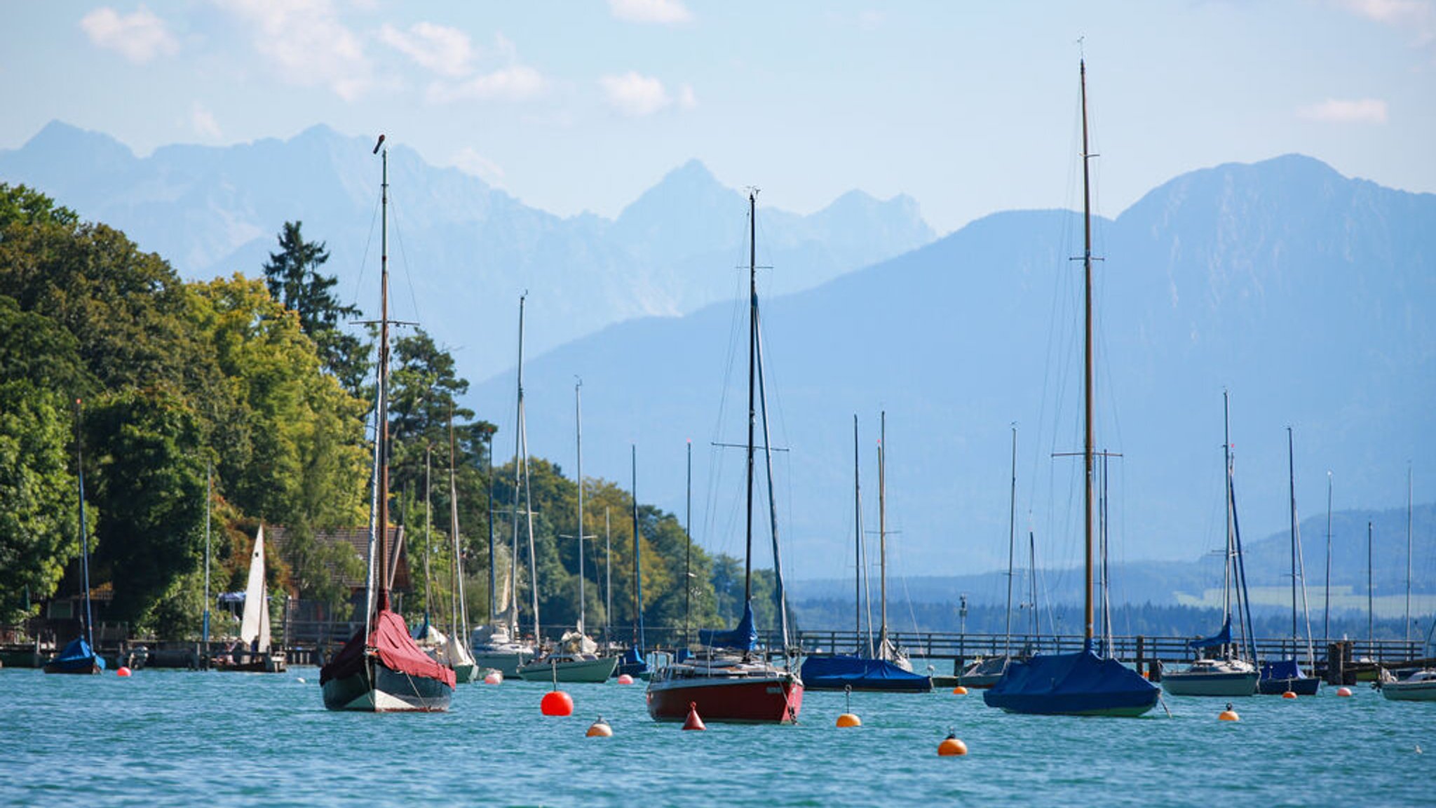 Segelboote am Starnberger See mit den bayerischen Alpen im Hintergrund.