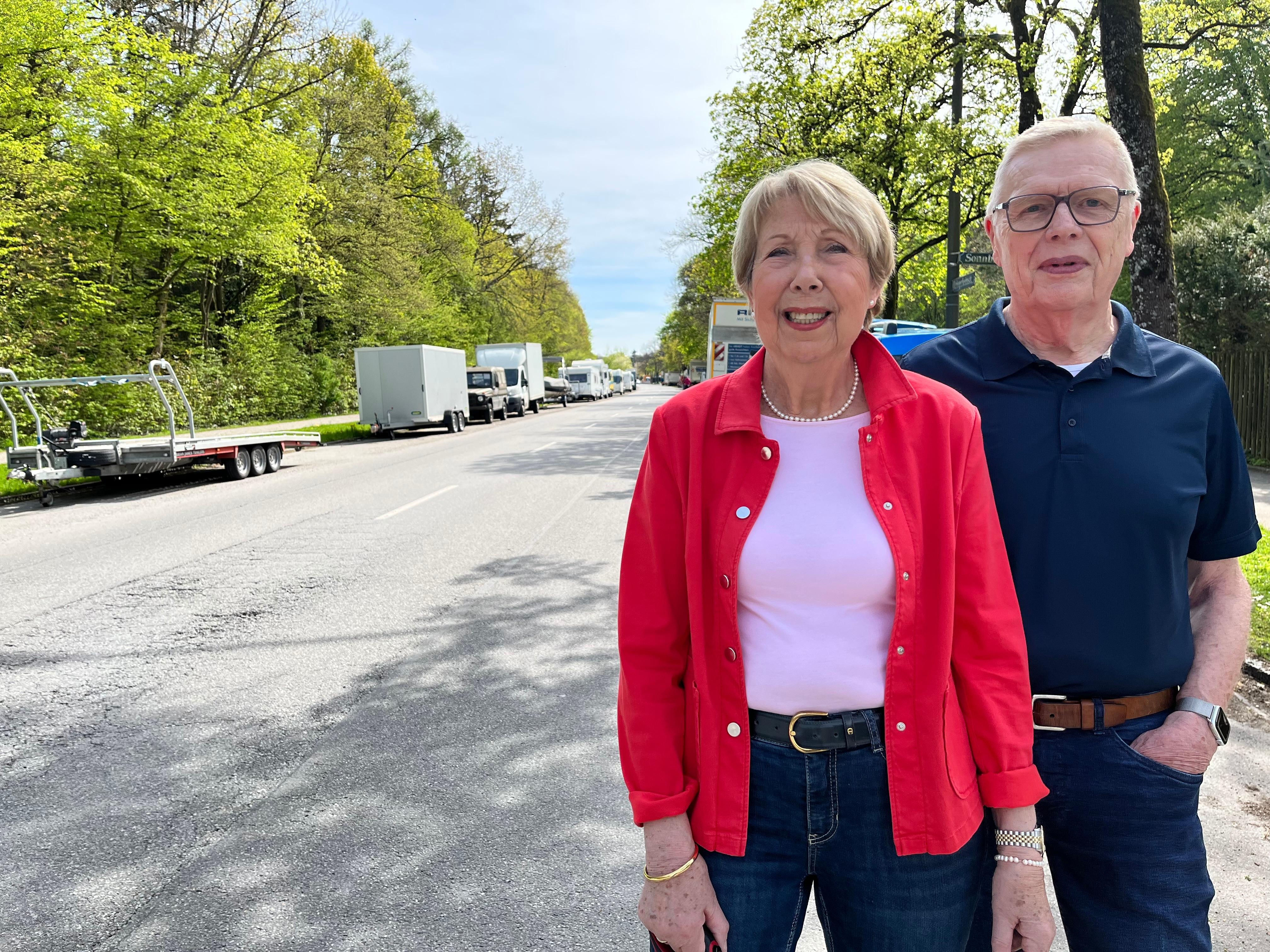 Ulla und Uli Haurand auf ihrer Straße am Münchner Waldfriedhof. Der  Seitenstreifen ist fast komplett mit Wohnmobilen und Anhängern zugestellt. 