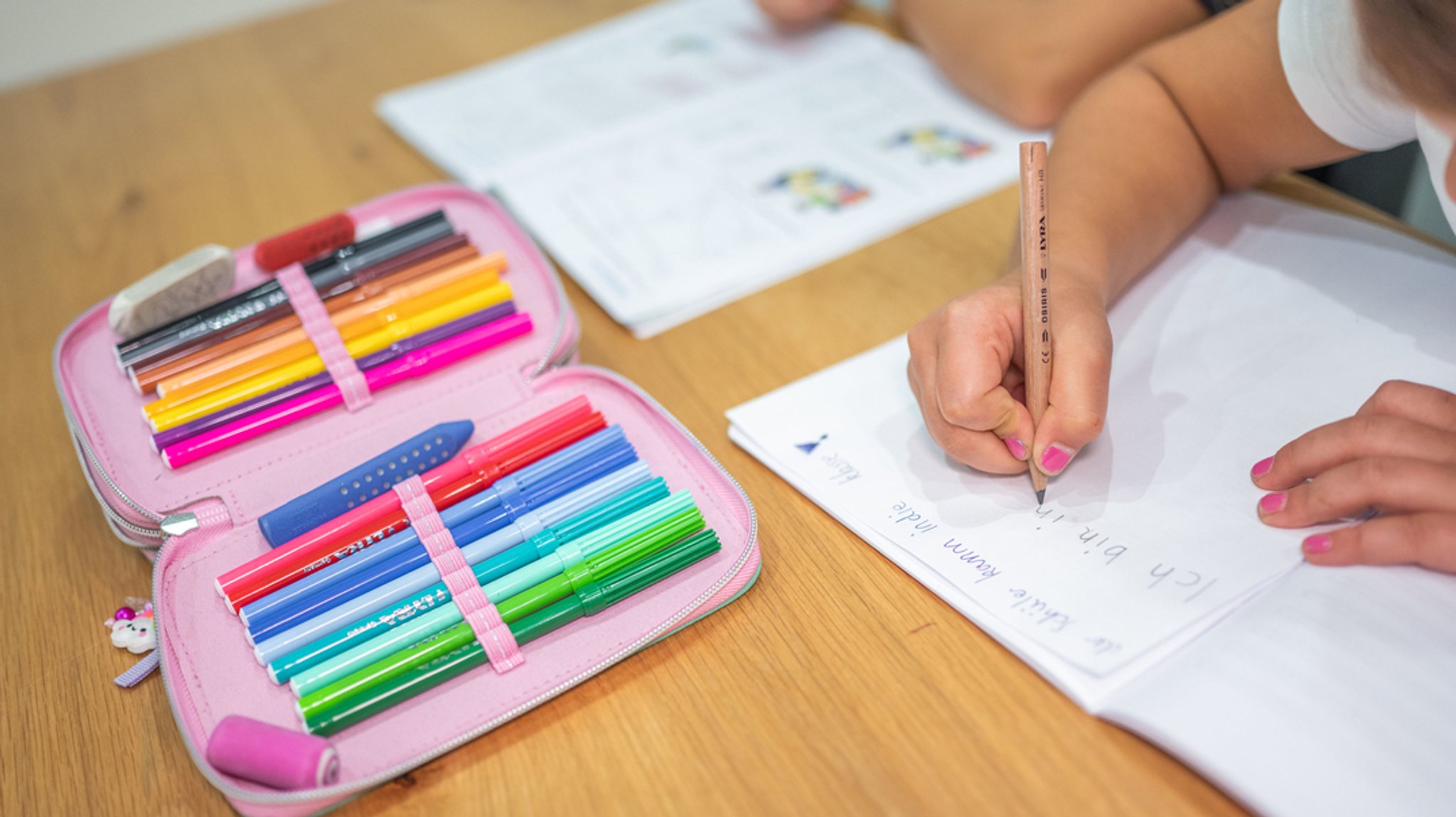 Ein Grundschüler und eine Grundschülerin sitzen am Tisch und erledigen Schulaufgaben