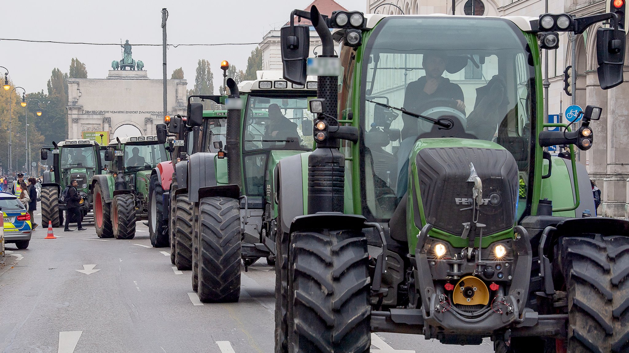 München: Traktoren fahren hintereinander zu einer Demonstration auf der Ludwigstrasse zwischen Siegestor (im Hintergrund) und Odeonsplatz