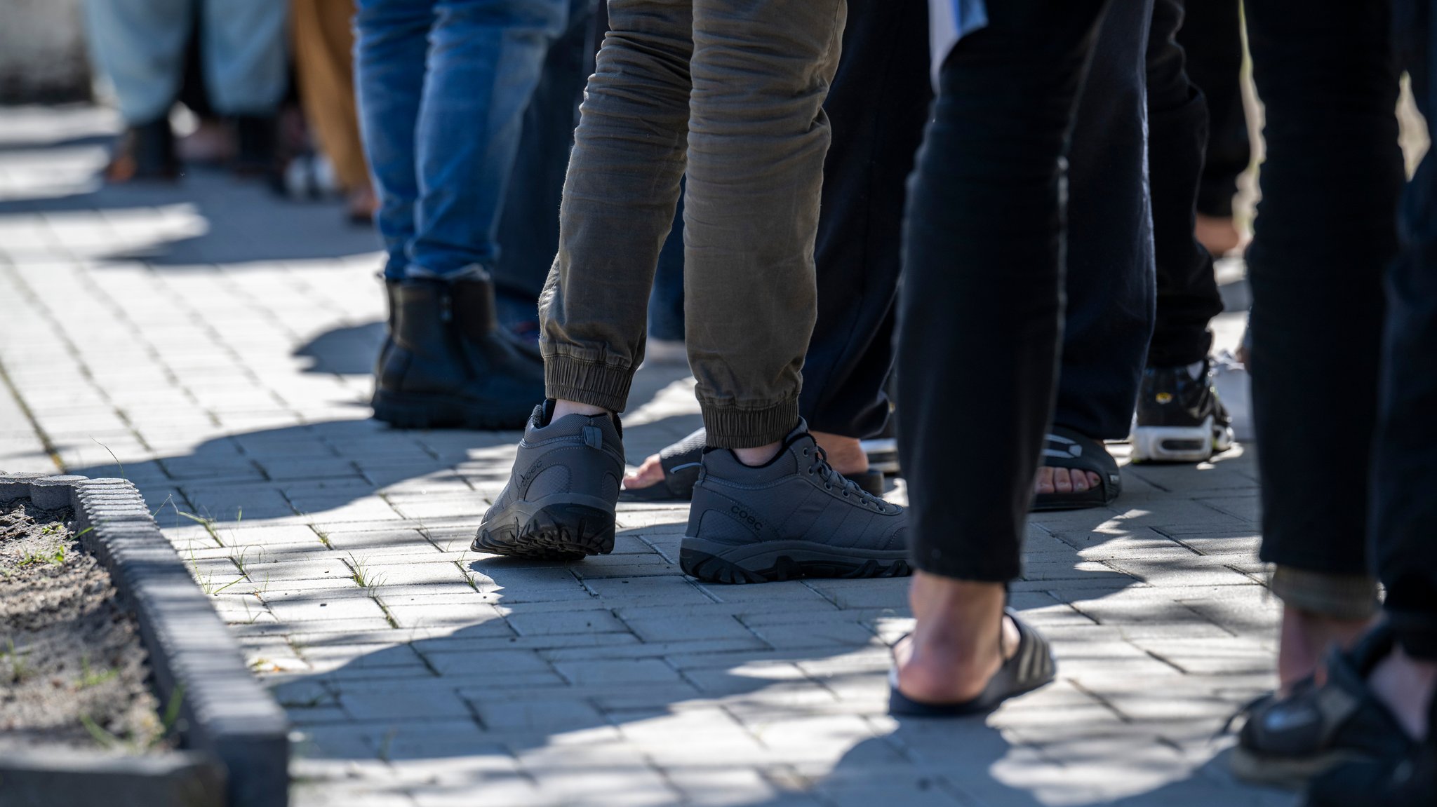 Migranten stehen in einer Schlange in einer Erstaufnahme-Einrichtung.