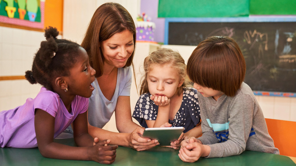 Erzieherin und Kinder mit Tablet Computer online im Kindergarten oder in der Vorschule