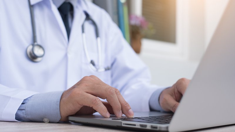 Ein Arzt tippt etwas auf dem Laptop. | Bild: stock.adobe.com/tippapatt Ein Arzt tippt etwas auf dem Laptop.