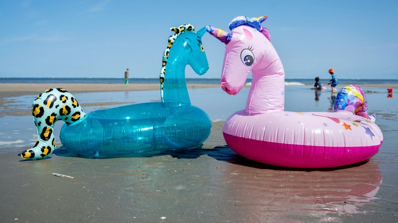 Aufblasbare Schwimmtiere und spielende Kinder am Strand (Symbolbild) | Bild: pa/dpa/Hauke-Christian Dittrich Aufblasbare Schwimmtiere und spielende Kinder am Strand (Symbolbild)