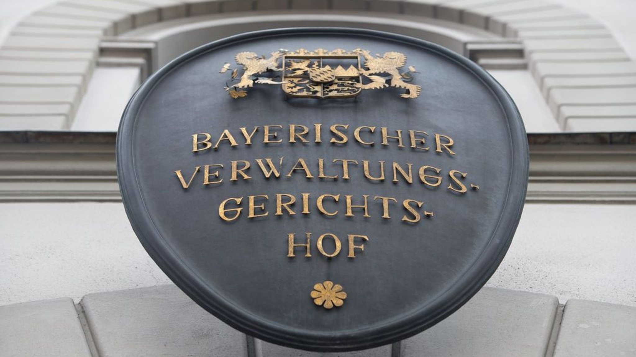 Ein Metallschild mit der Aufschrift "Bayerischer Verwaltungsgerichtshof" hängt an der Fassade des bayerischen Verwaltungsgerichtshofs.