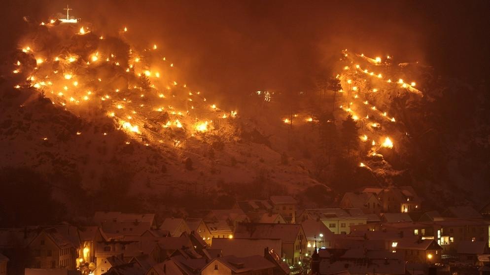 Blick auf Pottenstein und zahlreiche Bergfeuer im Schnee. 