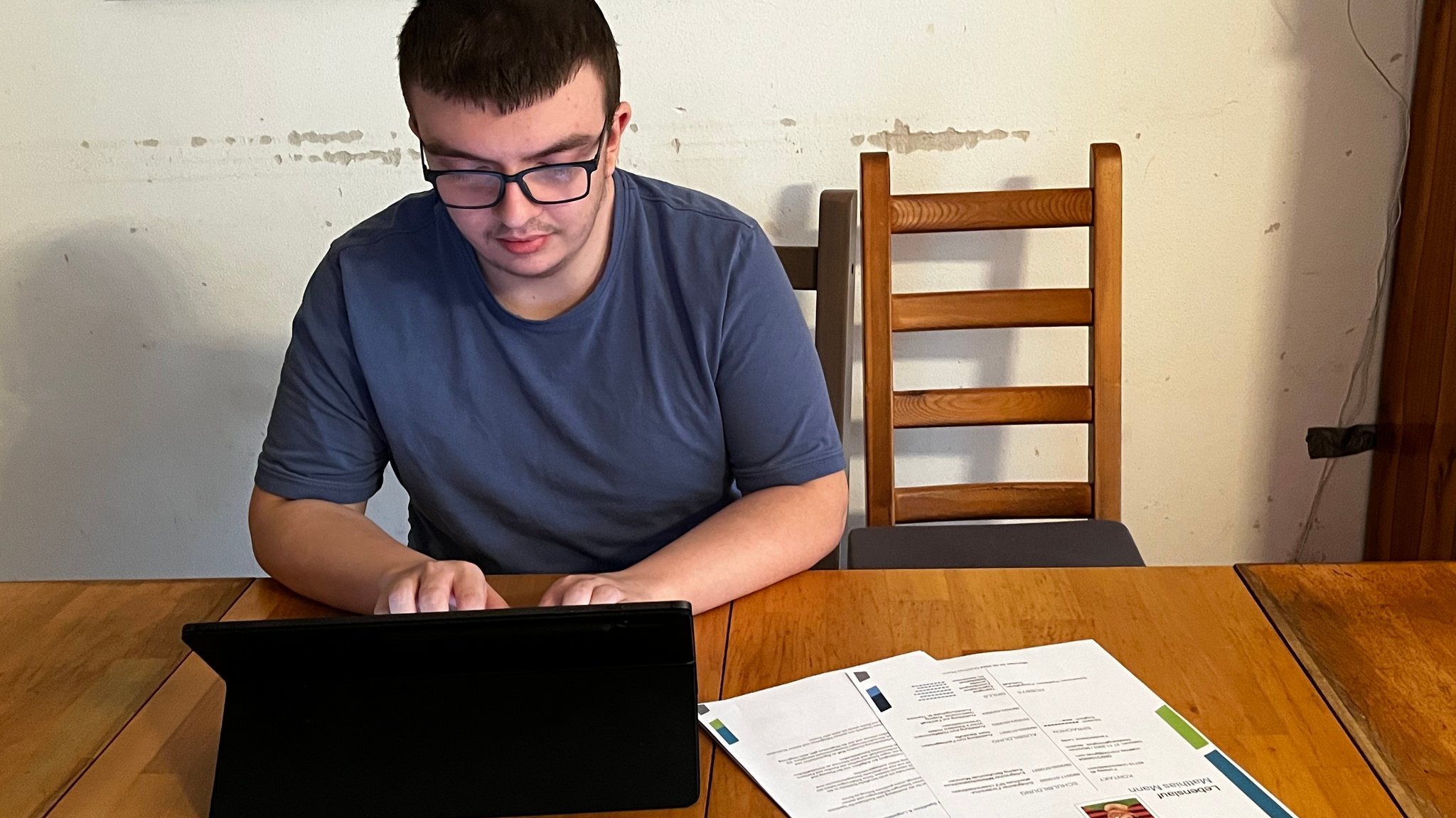 Matthias Mann am Laptop. Daneben liegen auf dem Tisch seine Bewerbungsunterlagen.