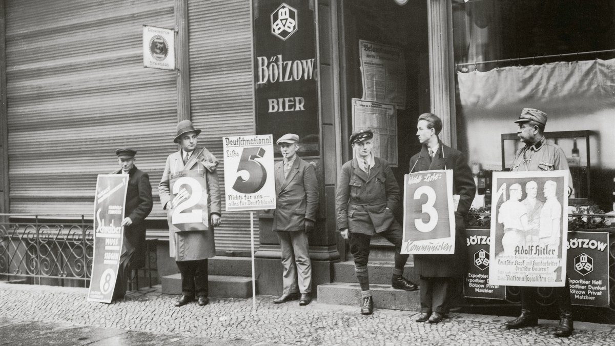 Für die Reichstagswahl in Berlin stellten Parteien vor den Wahllokalen Vertreter mit Plakaten auf. (6. November1932)