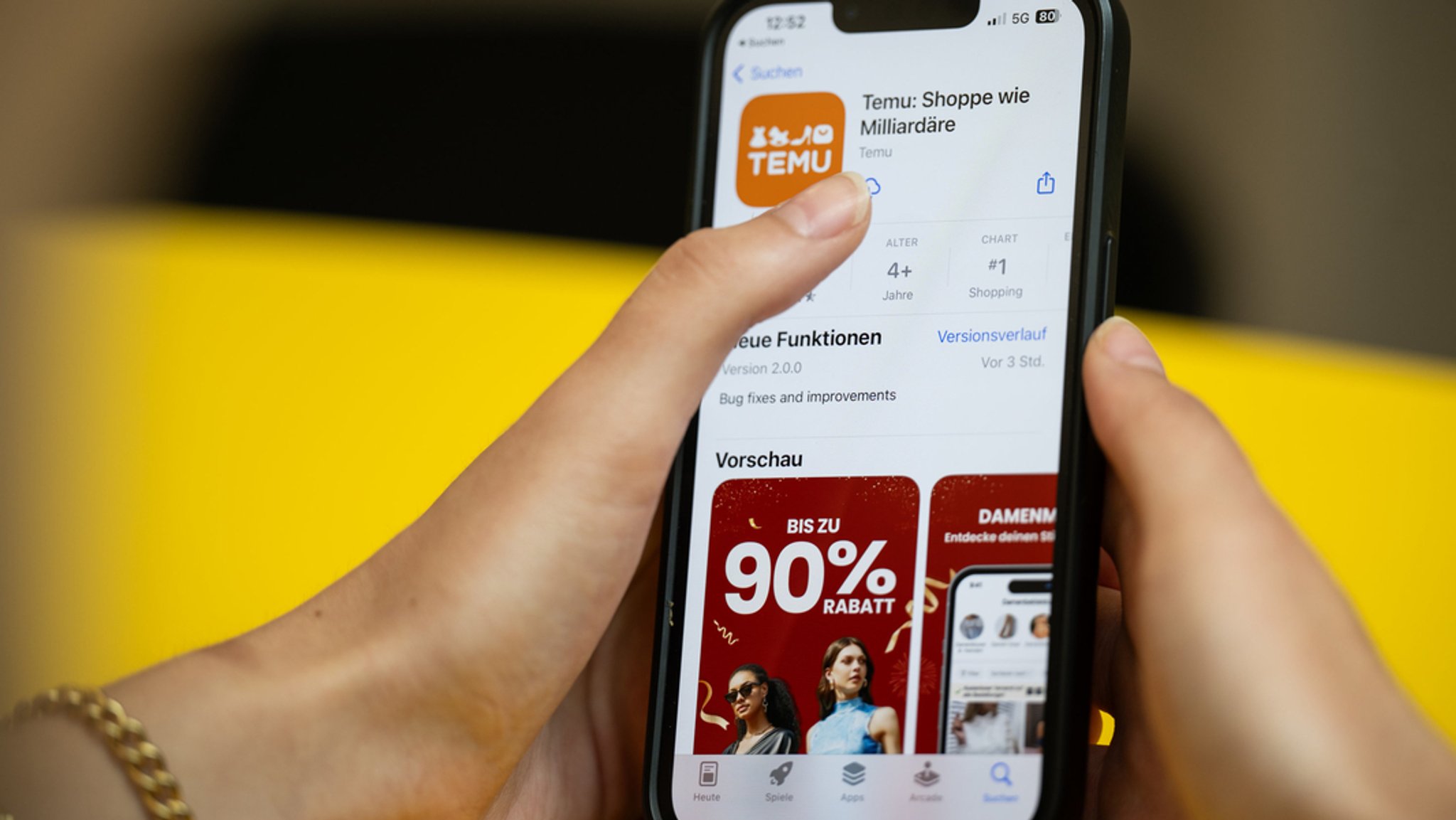 Eine Person hält ein Telefon mit der App Temu in den Händen. (Gestellte Szene).