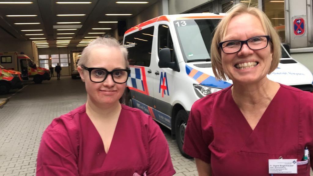 Pflegehelferin Anna Lena Bogenhauser steht mit ihrer Mutter vor der Notaufnahme der Uniklinik Augsburg. Sie arbeiten beide hier.