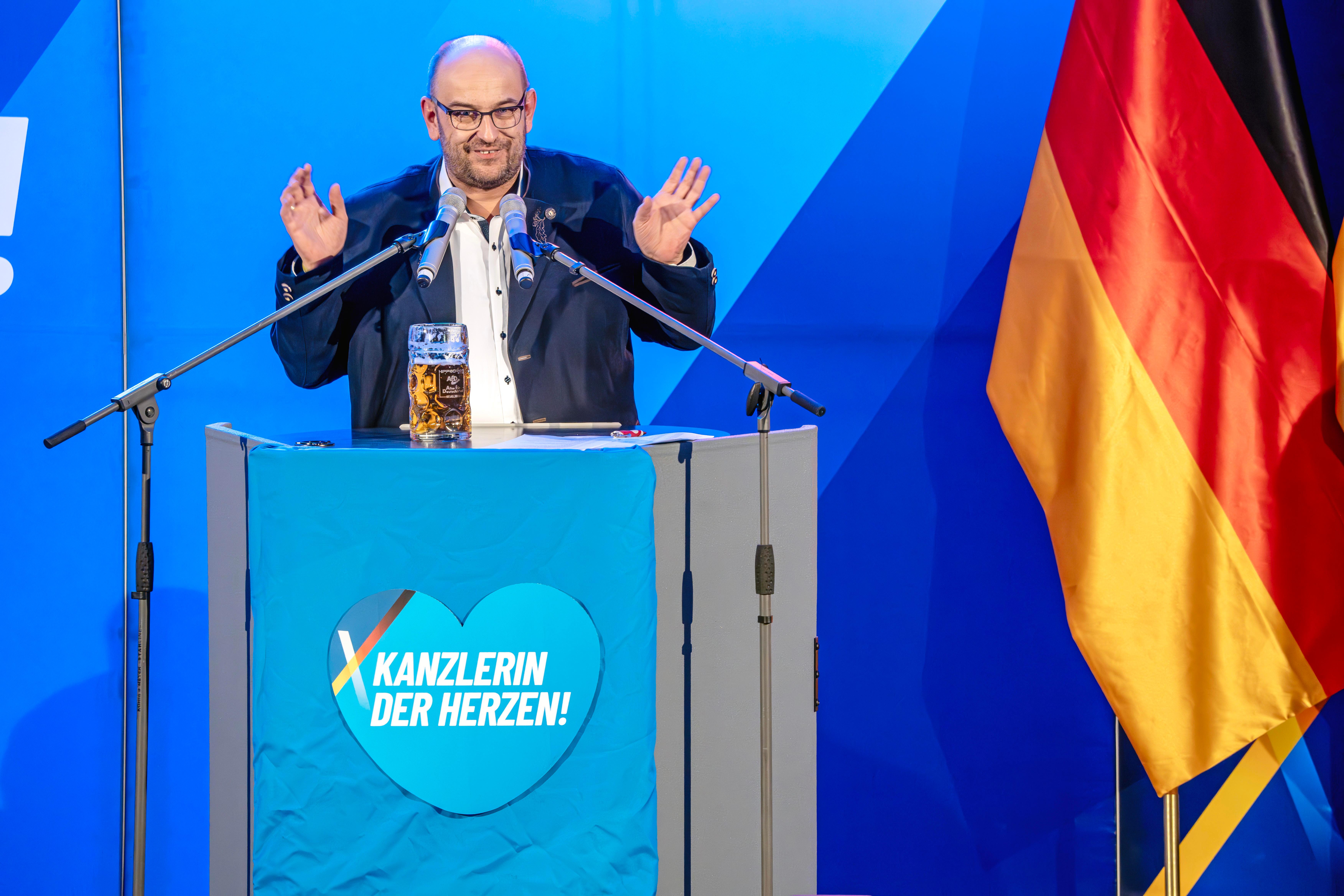Stephan Protschka, der aktuelle bayerische AfD-Landesvorsitzende, steht vor einem Rednerpult der AfD. 