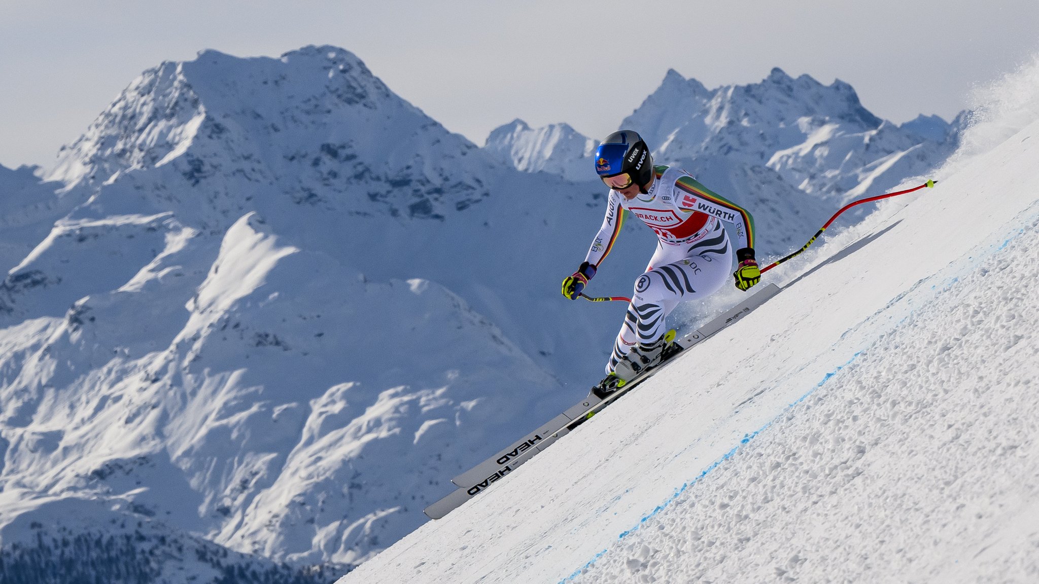 Emma Aicher auf der Abfahrtsstrecke. Im Hintergrund sind schneebedeckte Berge zu sehen.