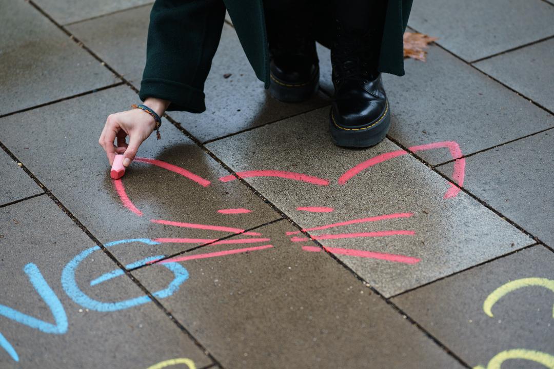 Eine Aktivistin malt mit Kreide ein Katzensymbol neben einen anzüglichen Kommentar aufs Straßenpflaster (Symbolbild).