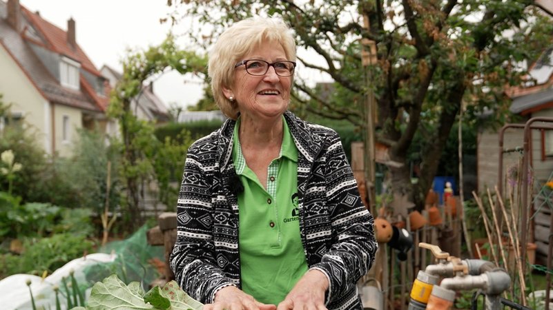 Eine blonde ältere Frau steht in ihrem Garten: Die "Garten-Moni".