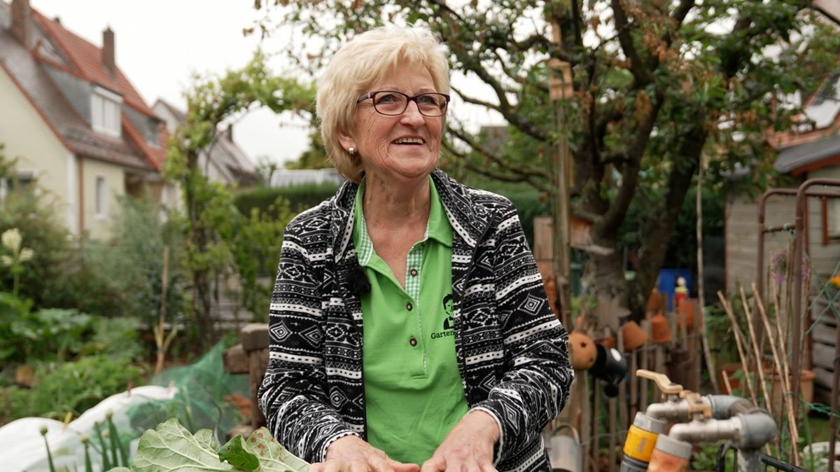 Eine blonde ältere Frau steht in ihrem Garten: Die "Garten-Moni".