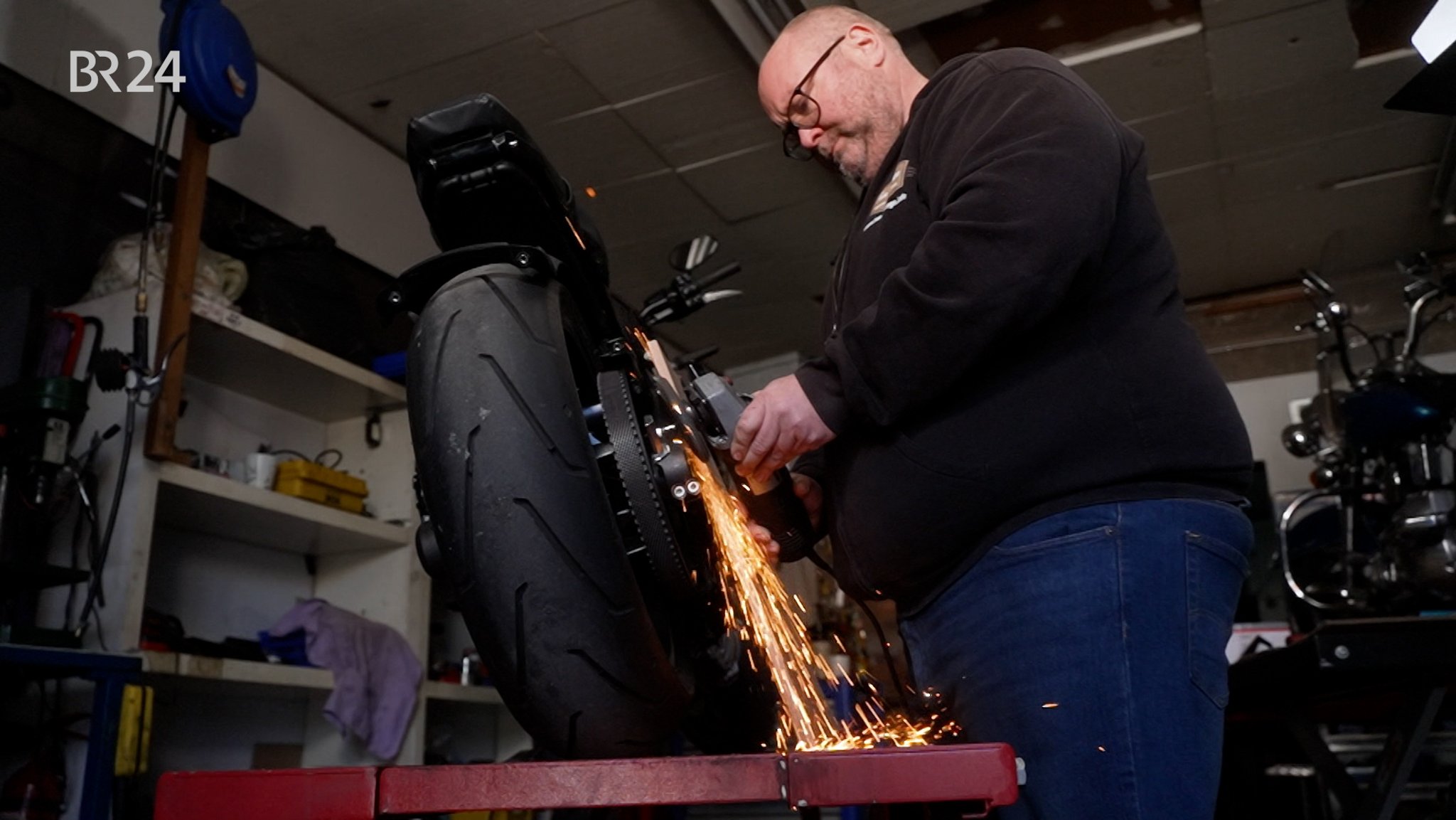 In einer Werkstatt schraubt ein Mann an einem Motorrad.