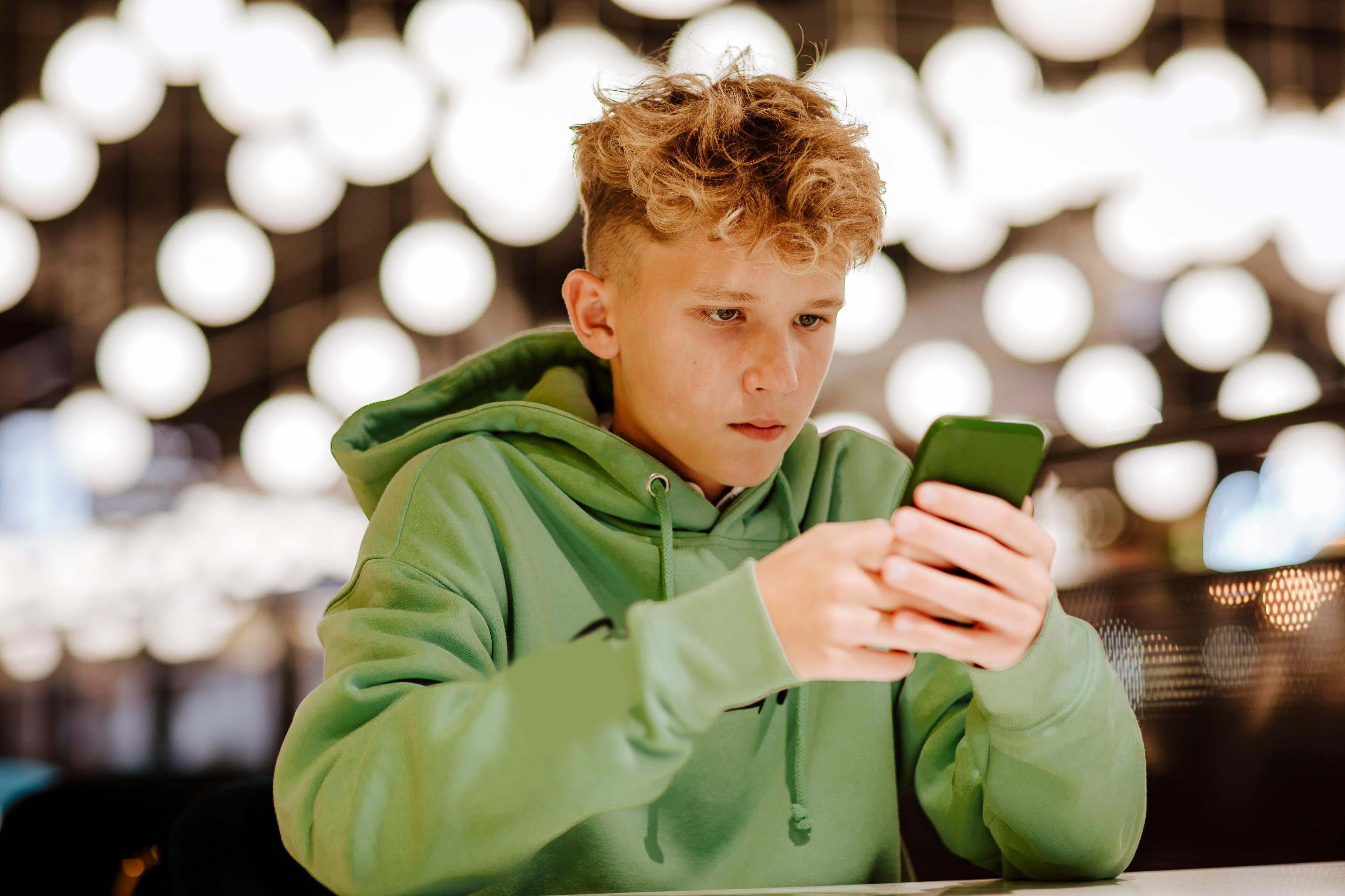 (Symbolbild) Teenager mit Smartphone in der Hand