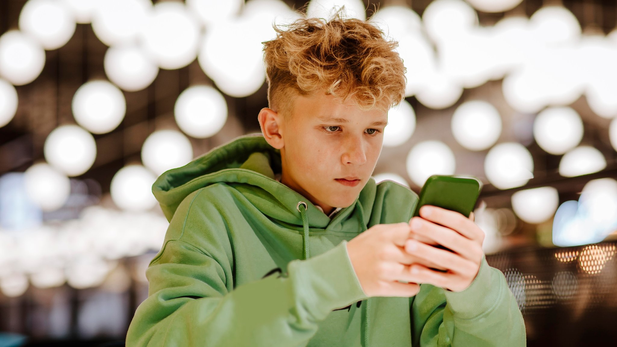 (Symbolbild) Teenager mit Smartphone in der Hand