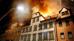 Feuerwehrleute bekämpfen brennende Häuser von einer Drehleiter.  | Bild:picture alliance / dpa