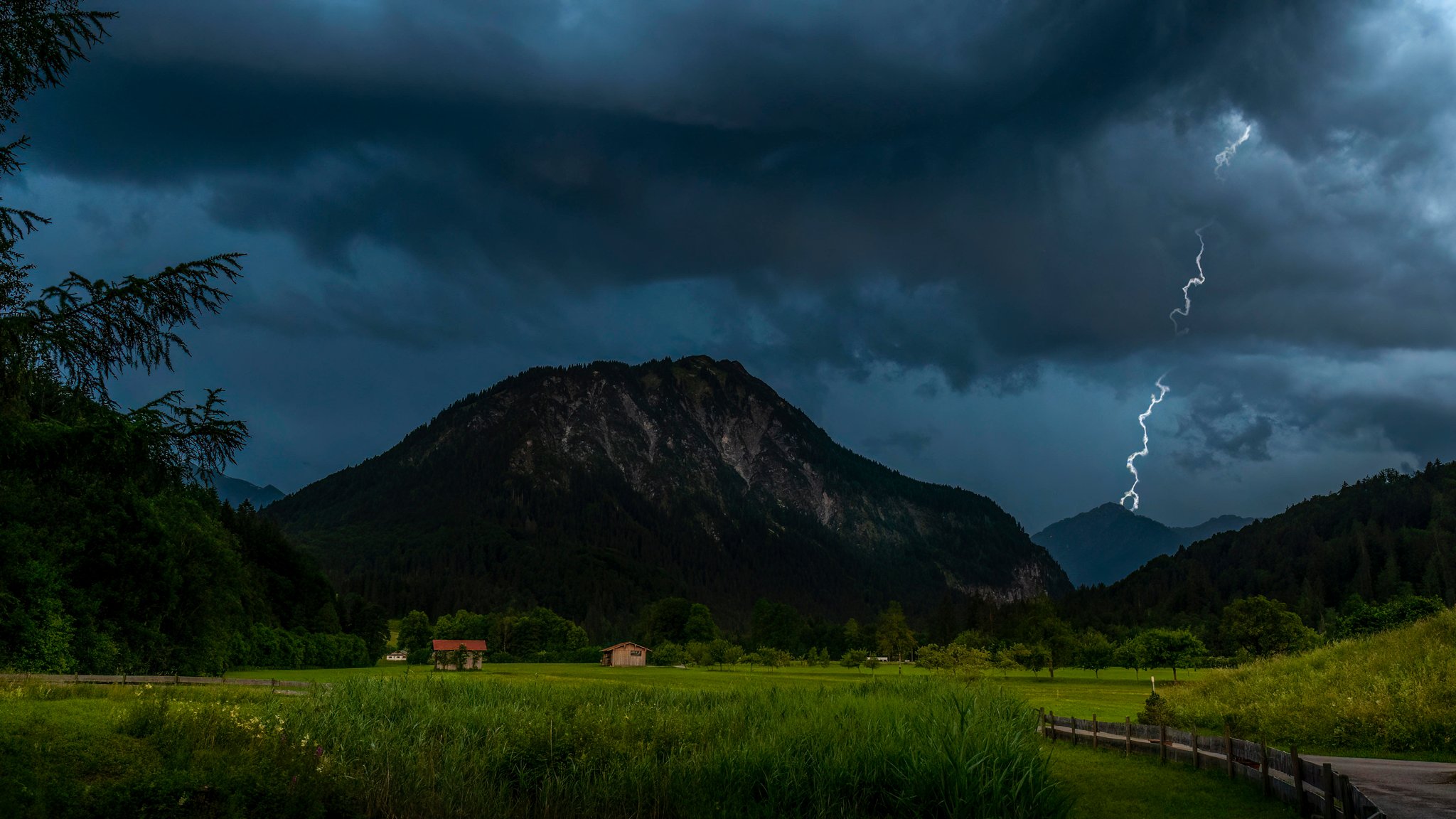 Dunkle Gewitterwolken verdunkeln den Himmel an einem Nachmittag über Bayern.