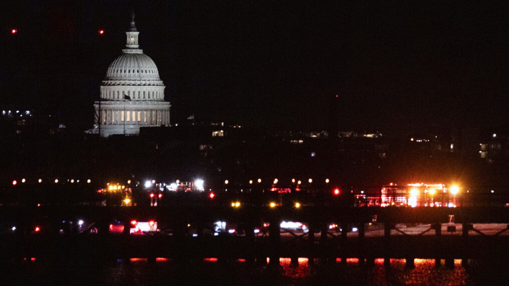 29.01.2025, USA, Alexandria: Notfallfahrzeuge stehen am Ronald Reagan Washington National Airport. Das US-Kapitol ist auf der anderen Seite des Potomac River in Washington zu sehen. Foto: Kevin Wolf/AP/dpa +++ dpa-Bildfunk +++