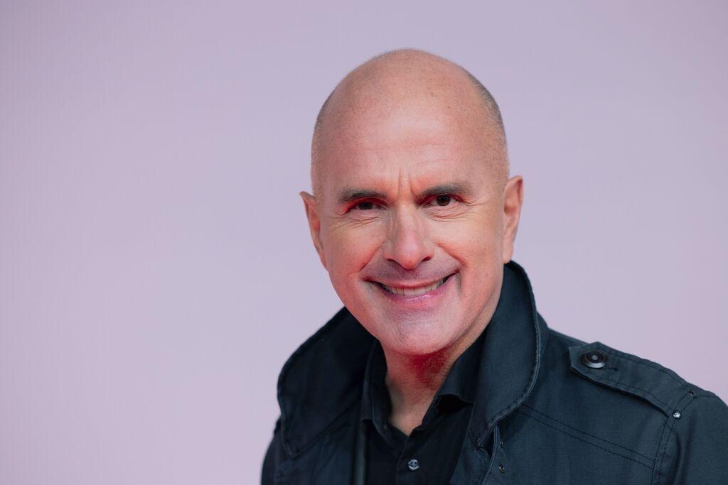 Der Schauspieler Christoph Maria Herbst vor einem lilafarbenen Hintergrund