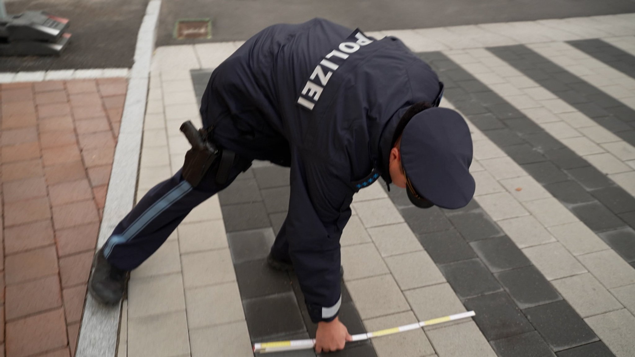 Polizist misst Breite des Zebrastreifens