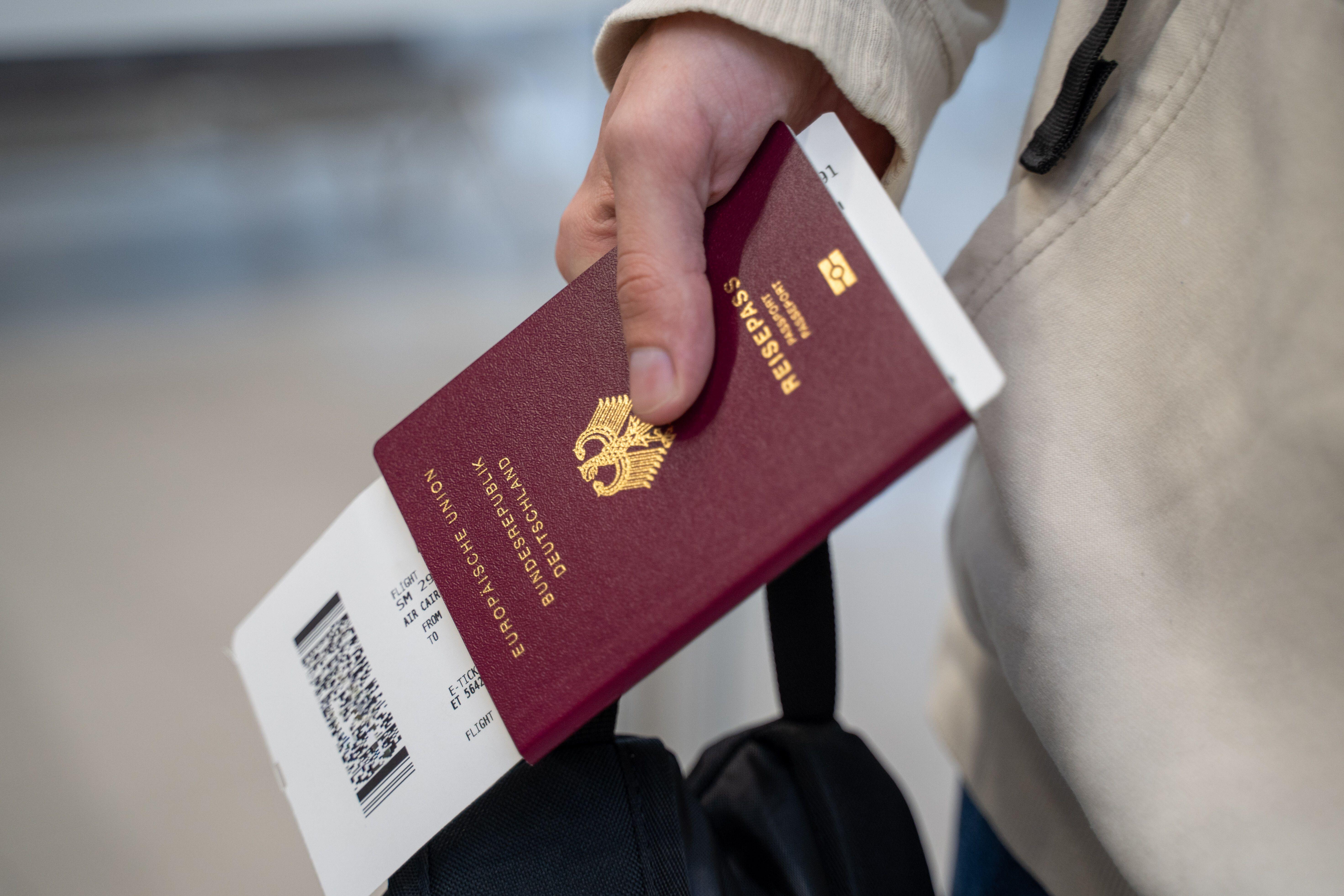 Ein biometrischer Reisepass und ein Flugticket in der Hand von einem Passagier.