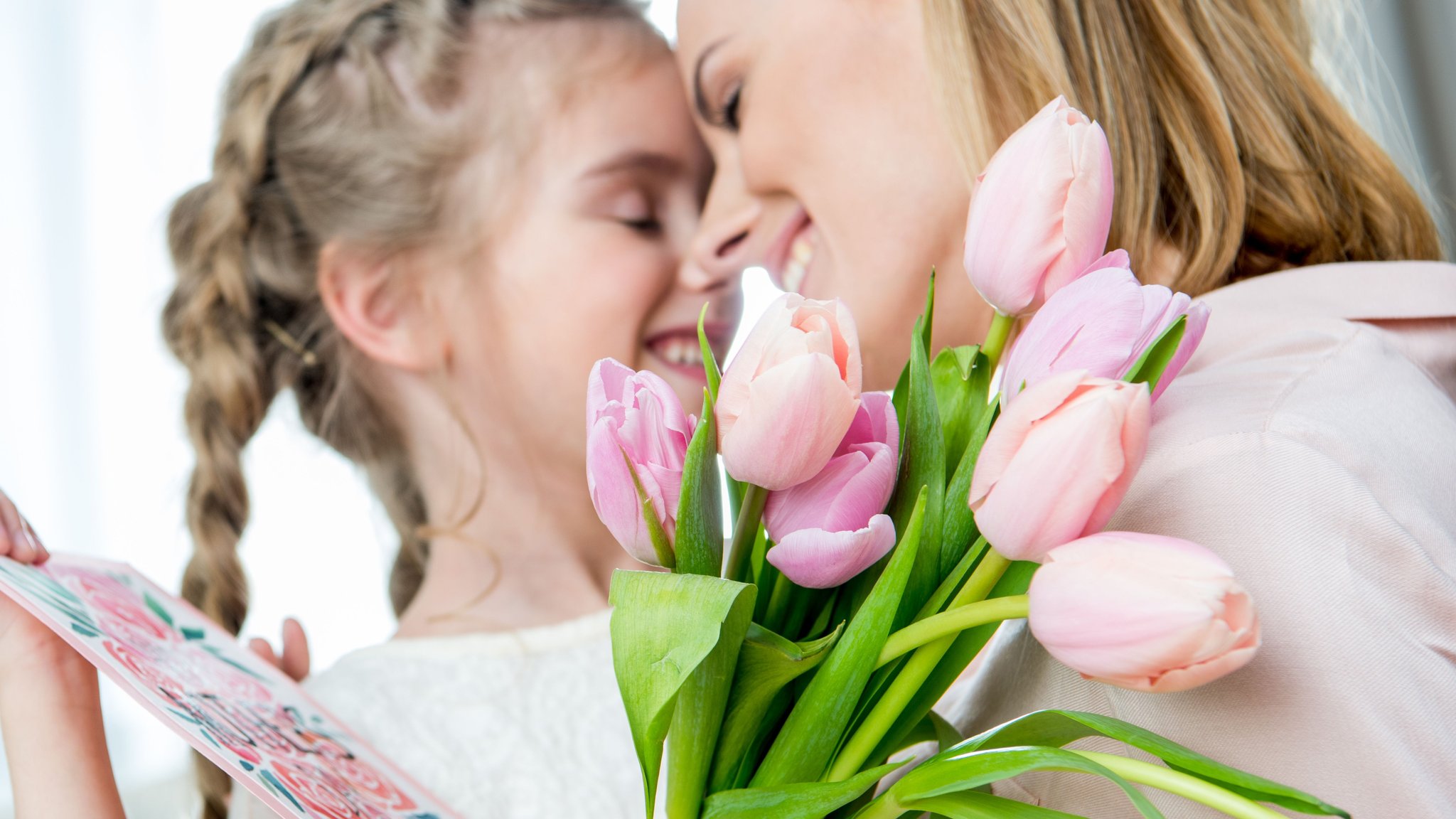 Kind überreicht Frau einen Tulpenstrauß