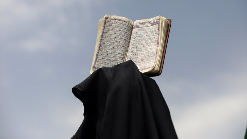 Ein Demonstrant hält einen Koran in die Höhe.