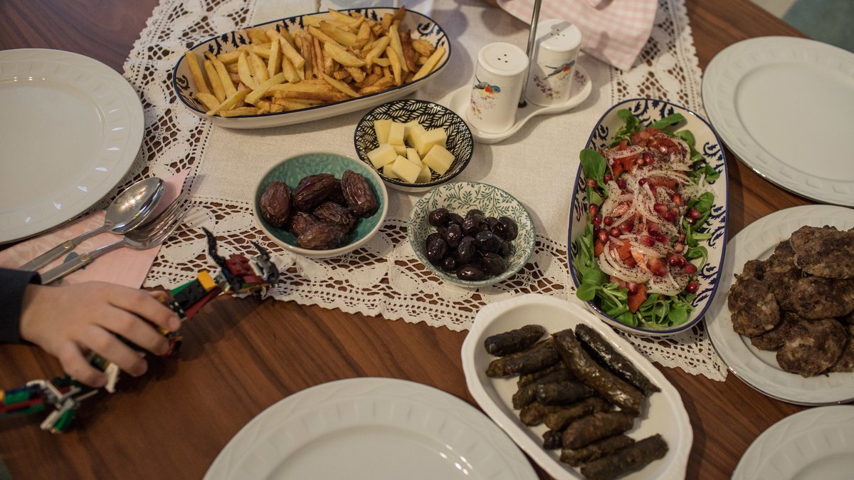 Auf einem Tisch stehen mehrere Schalen mit Pommes, Salat, Käse, Oliven und Datteln.