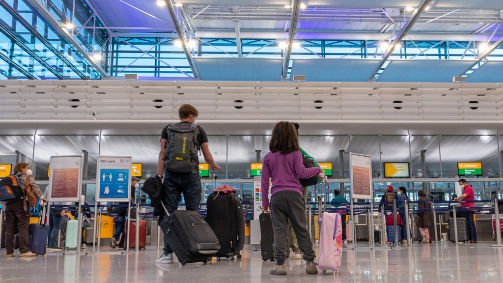 Passagiere am Flughafen München stehen an einem Check-in-Schalter an