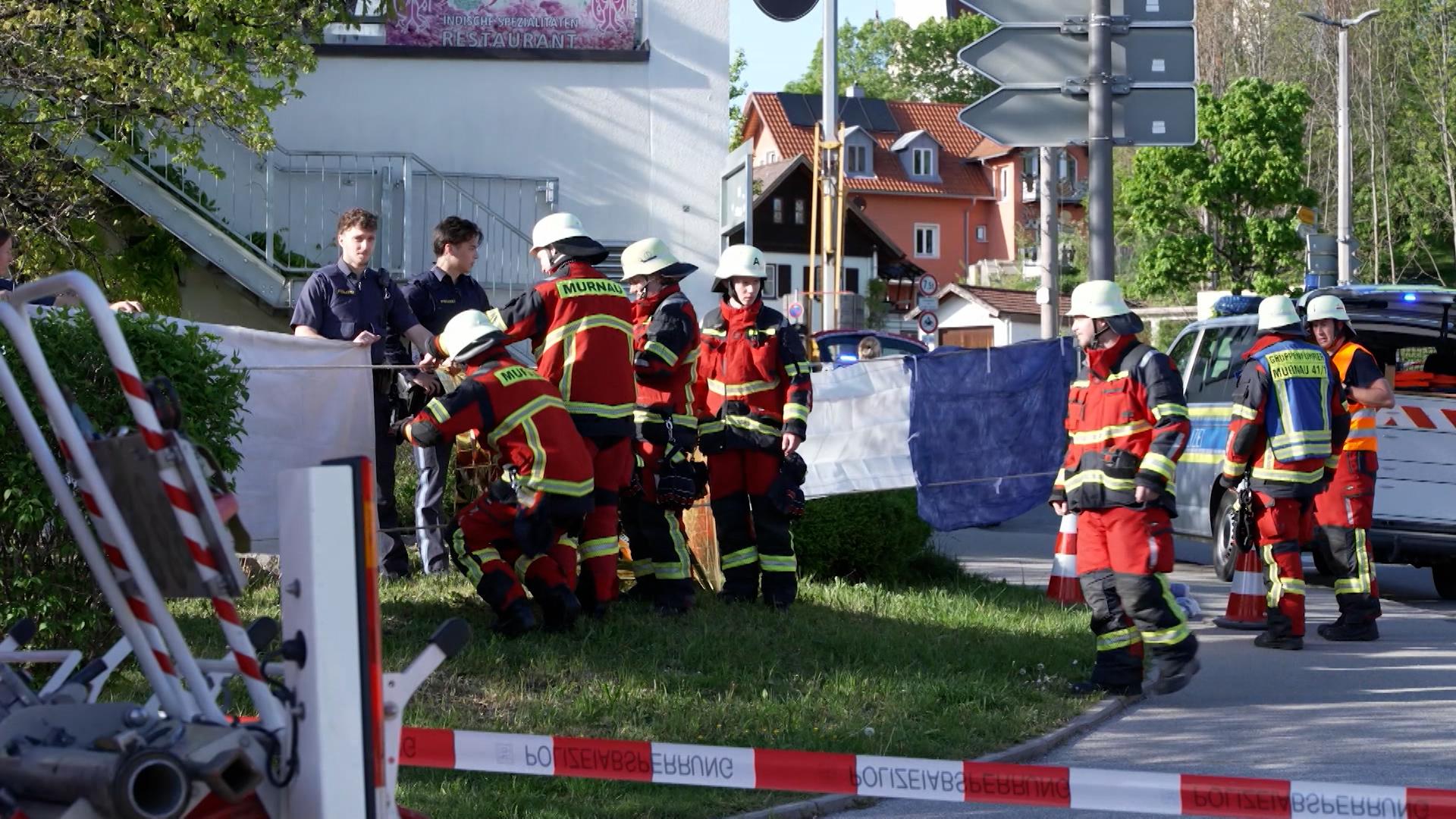 Feuerwehrleute und Polizeikräfte sichern den Tatort in Murnau am Samstag.