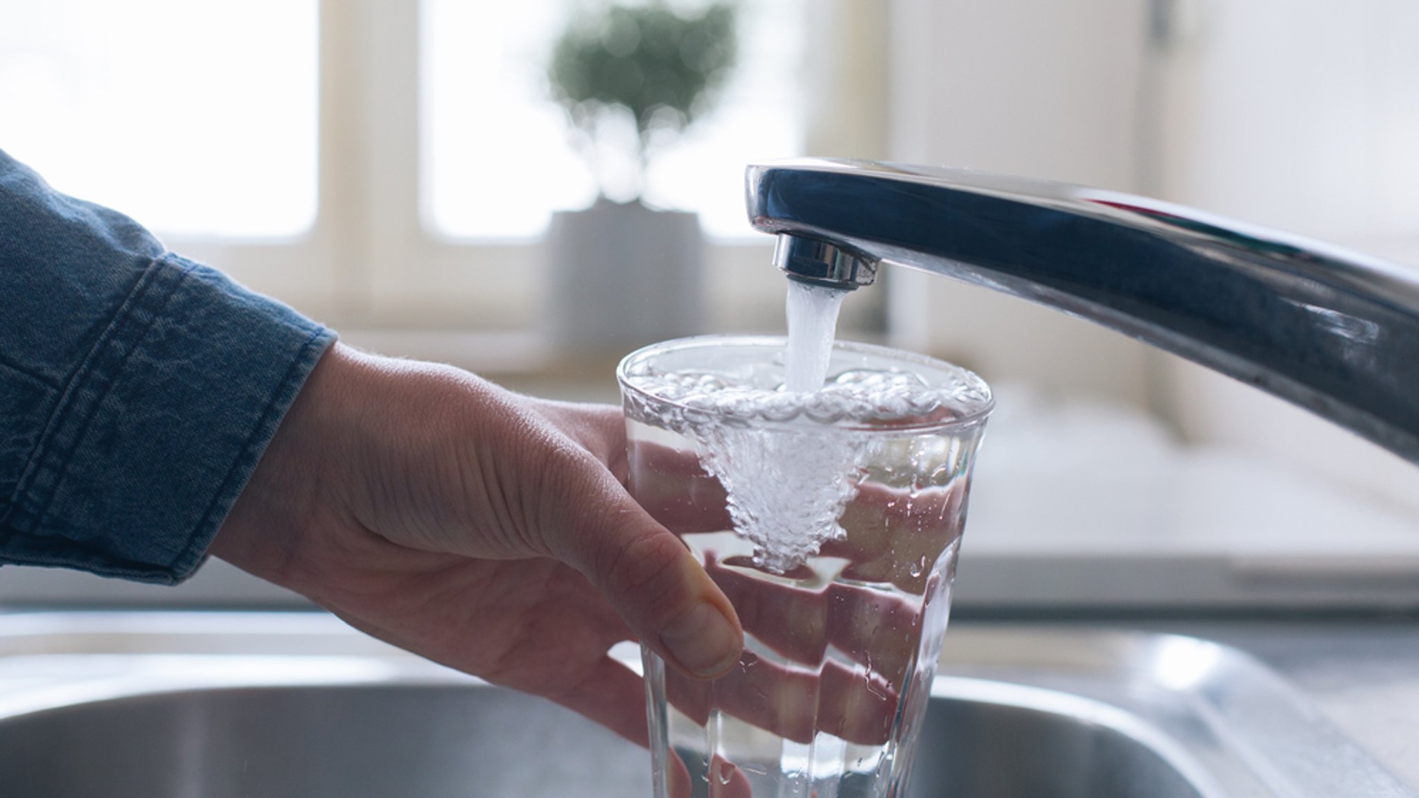 Mann füllt Wasserglas am Hahn (Symbolbild)