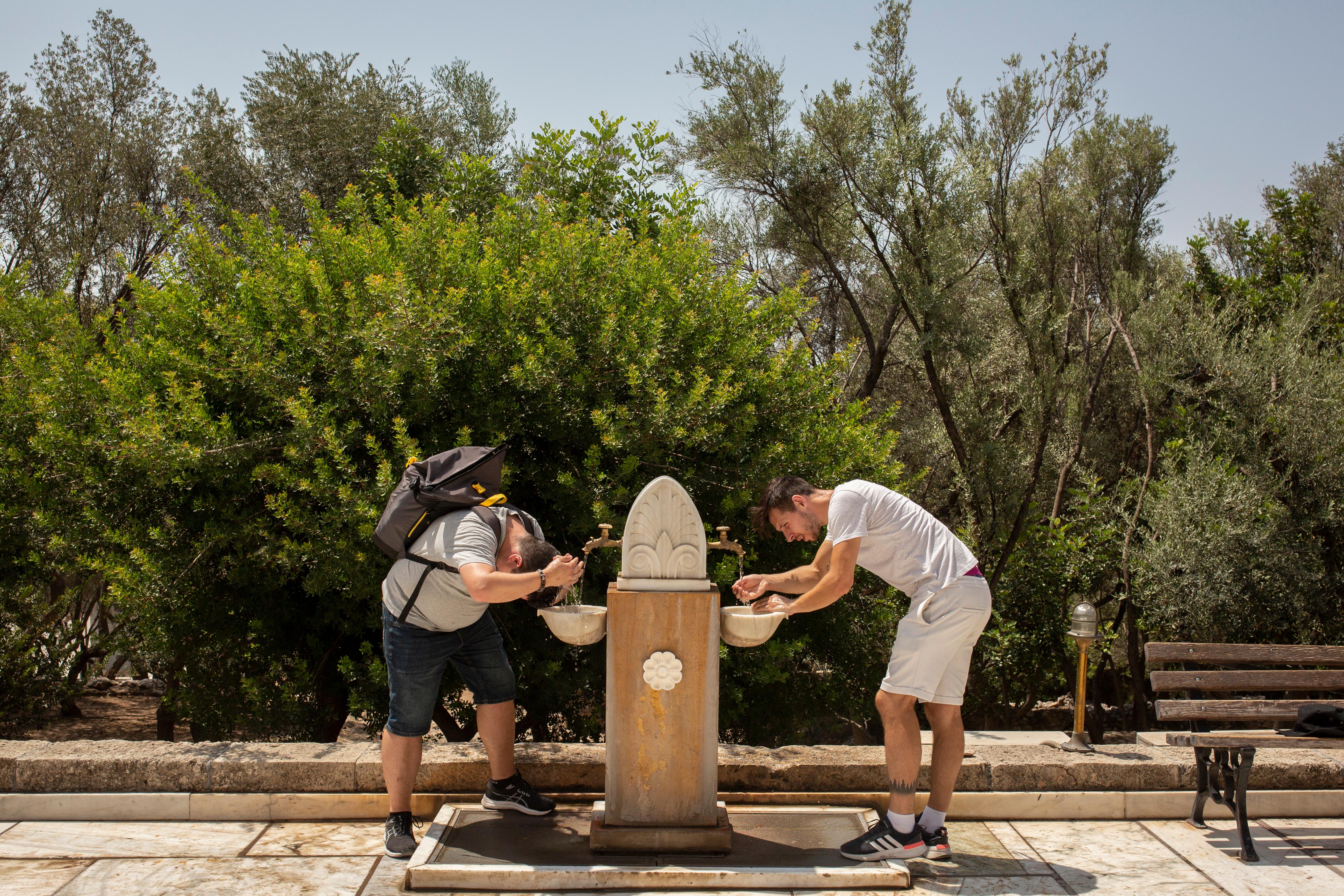 Touristen erfrischen sich während ihres Besuchs auf der Akropolis im Zentrum Athens an einem öffentlichen Trinkbrunnen. (Archivbild vom 21.7.23)