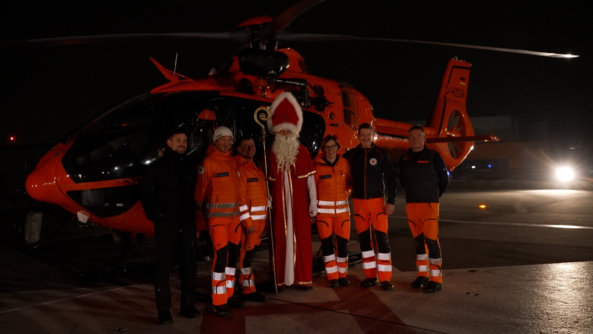 Der Nikolaus steht zusammen mit Rettungskräften vor dem Hubschrauber | Bild: BR/Laura Goudkamp Der Nikolaus steht zusammen mit Rettungskräften vor dem Hubschrauber