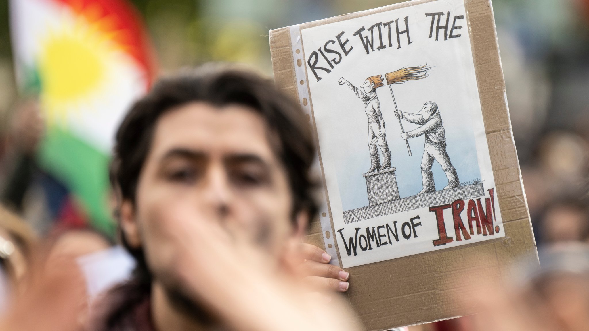 Demonstrantinnen und Demonstranten während einer Kundgebung gegen das politische Regime im Iran. Dabei steht auf einem Schild "Rise with the women of Iran".