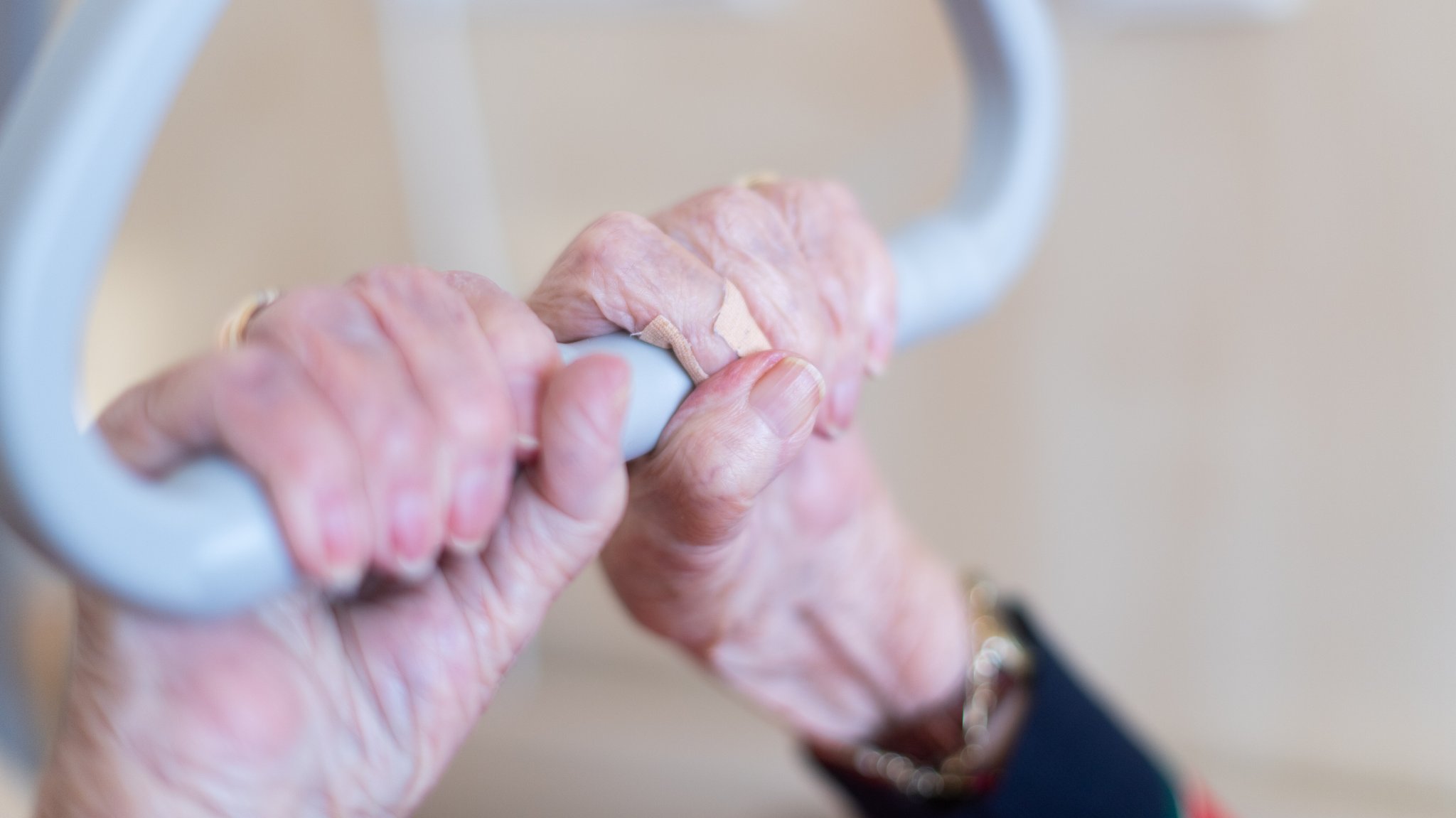 Die Hände einer Bewohnerin eines Pflegeheims halten sich an einem dreieckigen Haltegriff. über ihrem Bett fest. | Bild: picture alliance/dpa | Tom Weller Die Hände einer Bewohnerin eines Pflegeheims halten sich an einem dreieckigen Haltegriff. über ihrem Bett fest.