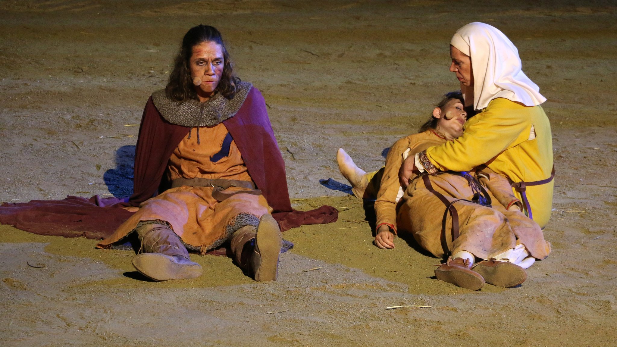 Der Bauernsohn sitzt im Sand neben Mutter und Schwester