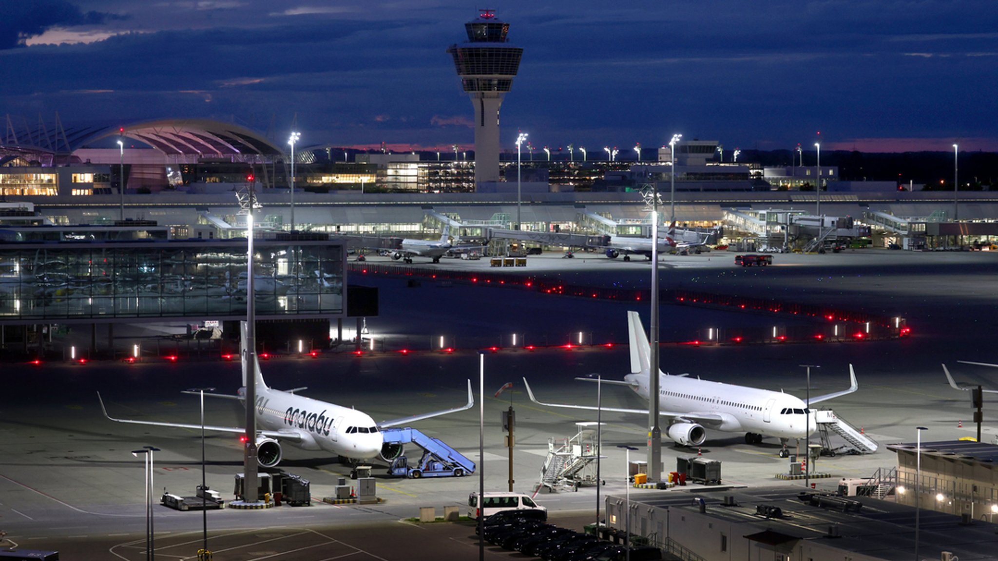 Flughafen München in der Dämmerung mit zwei Maschinen im Vordergrund