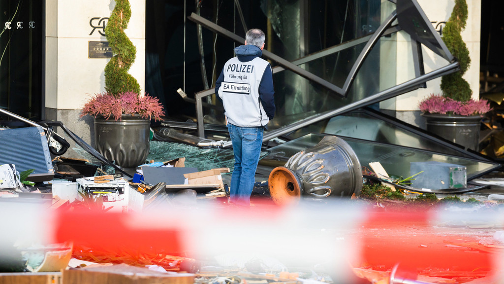 16.12.2022, Berlin: Ein Polizeibeamter begutachtet auf der Karl-Liebknecht-Straße Trümmer vor einem Hotel.