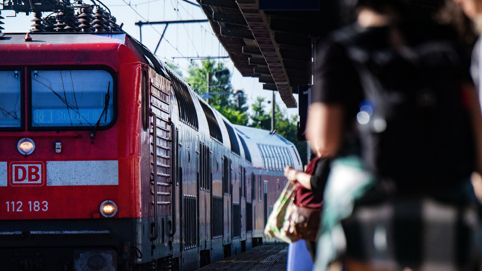 Ausflügler warten am Bahnsteig auf einen Zug der Deutschen Bahn