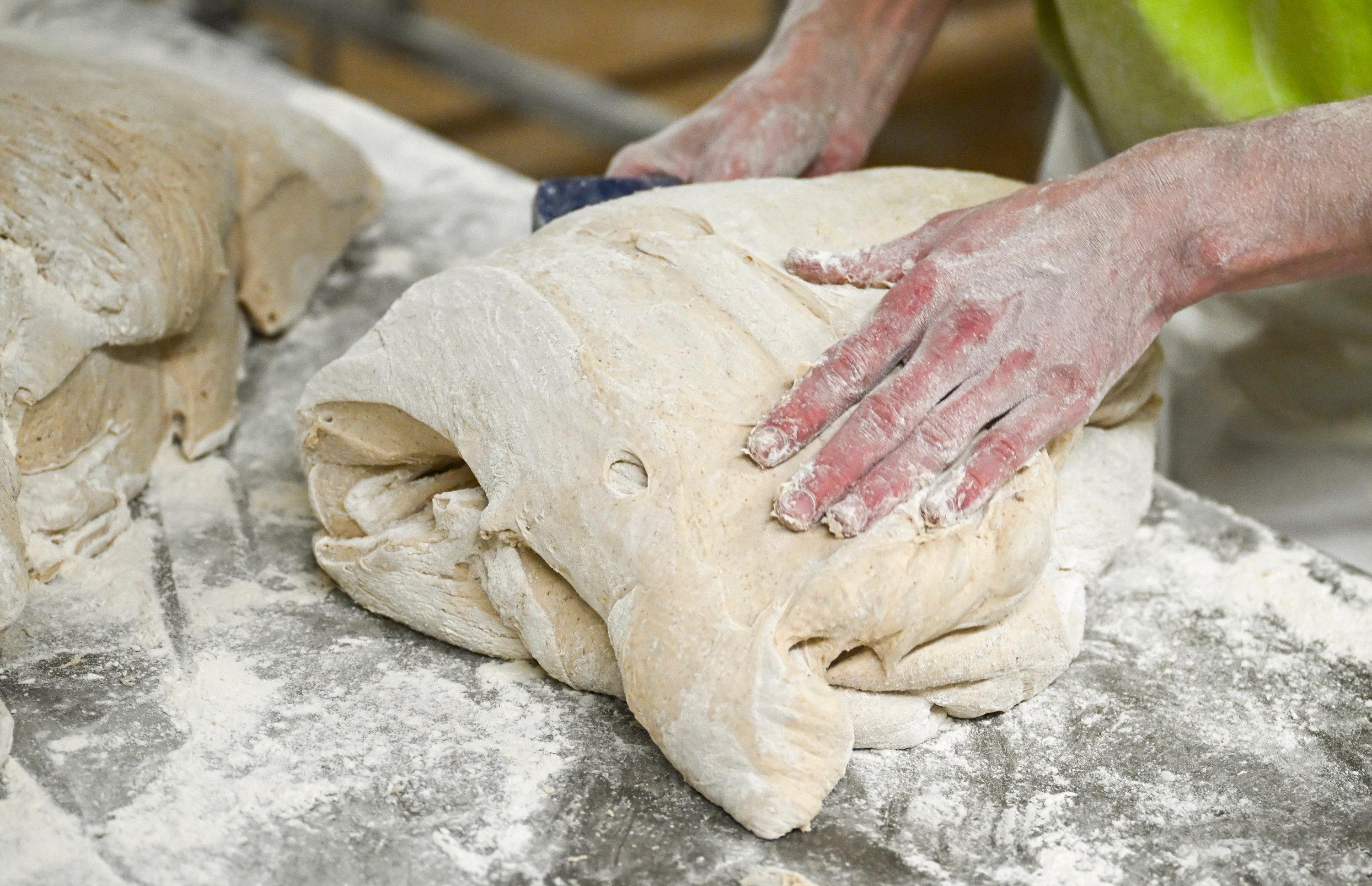 Auszubildender knetet Brotteig (Symbolbild)