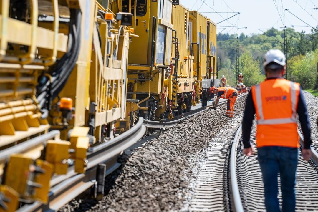 Bauarbeiter und Maschinen an Bahnstrecke. 