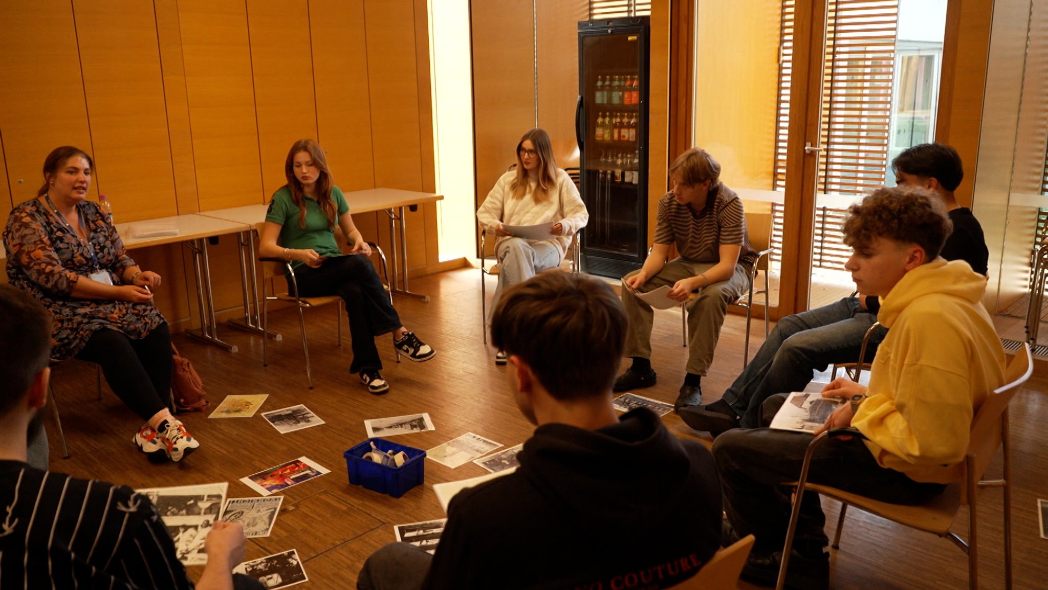 Jugendliche sitzen vor Fotos in einem Workshop.