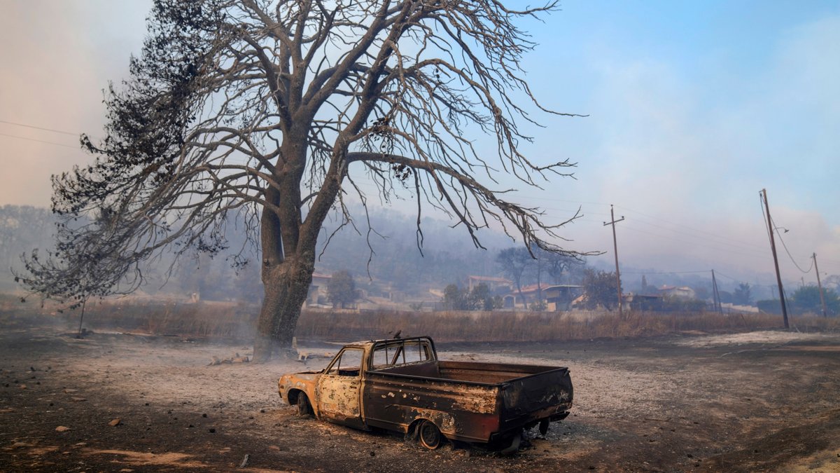 Griechenland, Loutraki: Ein ausbebranntes Auto steht vor einem verbrannten Baum in der Nähe von Loutraki.